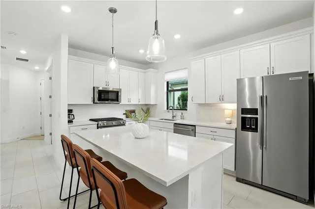 a kitchen with stainless steel appliances a table chairs refrigerator and microwave