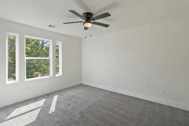 an empty room with a window and a fan