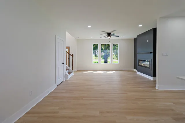 a view of an empty room with a window and a kitchen