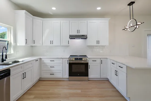 a kitchen with white cabinets stainless steel appliances and sink