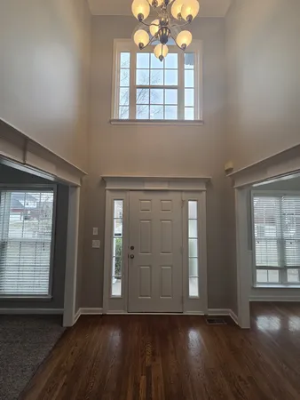 an empty room with wooden floor cabinet and windows