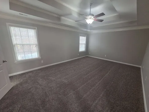 an empty room with windows and chandelier fan