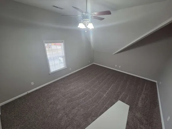 an empty room with windows and fan