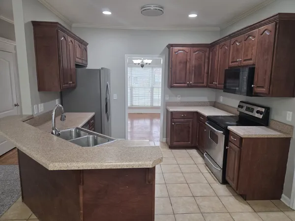 a kitchen with stainless steel appliances granite countertop a sink stove microwave and refrigerator