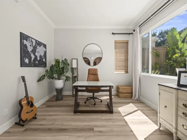 a living room with furniture two large windows and a dining table