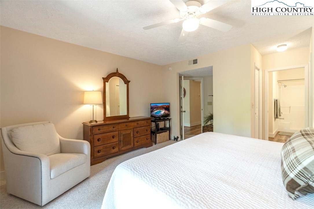 166 Still Lake Drive, Unit 222 Boone, NC 28607 - Photo 20 of 37 a spacious bedroom with a bed a chandelier and a dresser