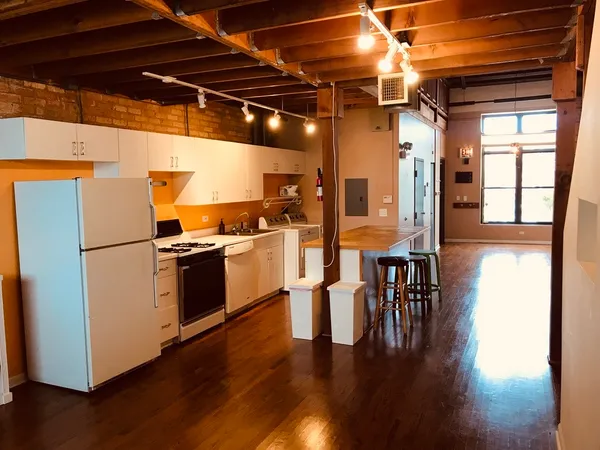 a kitchen with granite countertop a refrigerator a stove and wooden floor
