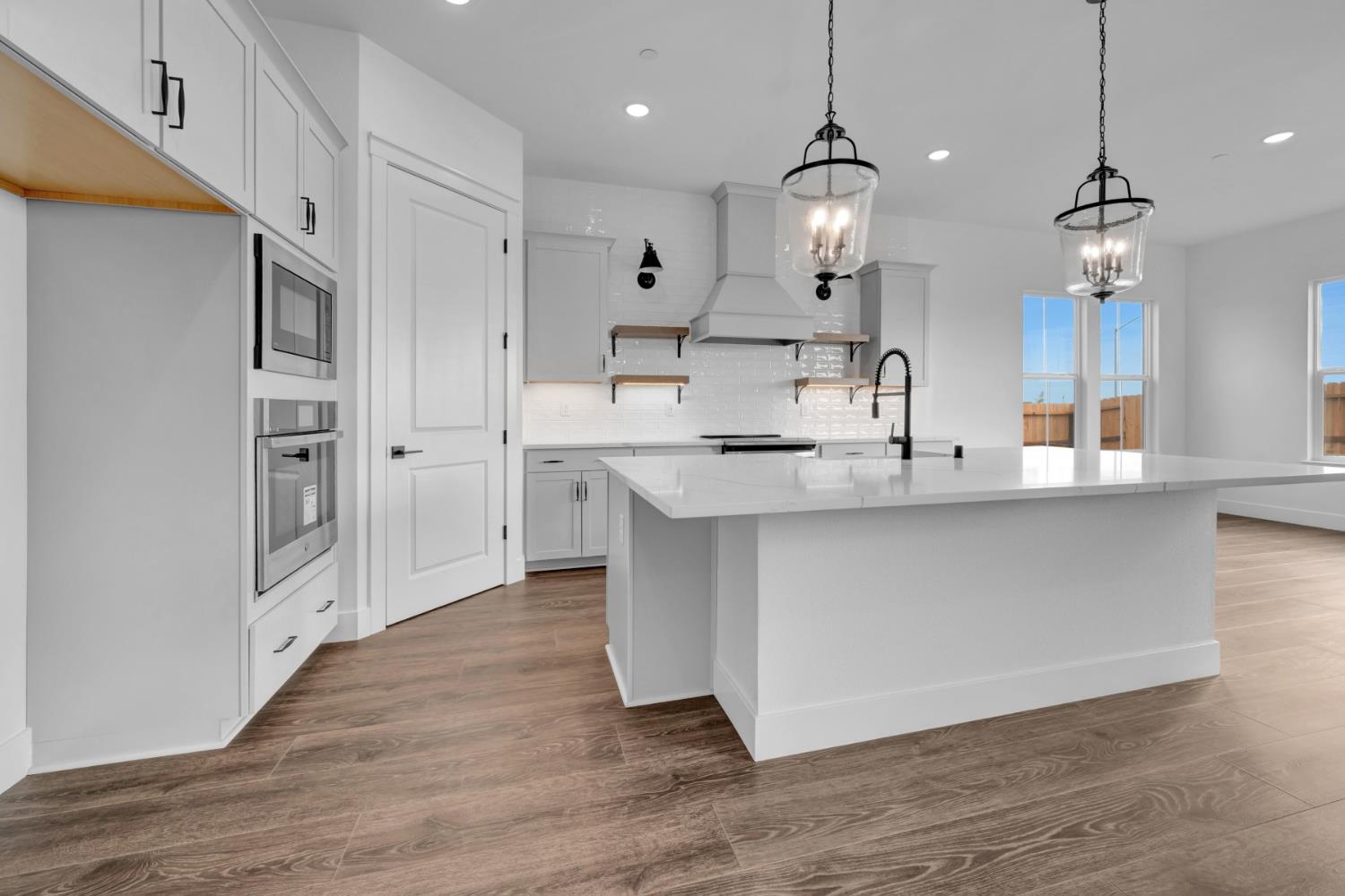 4327 Hooded Crow Way Rancho Cordova, CA 95742 - Photo 10 of 58 a large kitchen with stainless steel appliances kitchen island granite countertop a refrigerator a stove a sink and a wooden floors