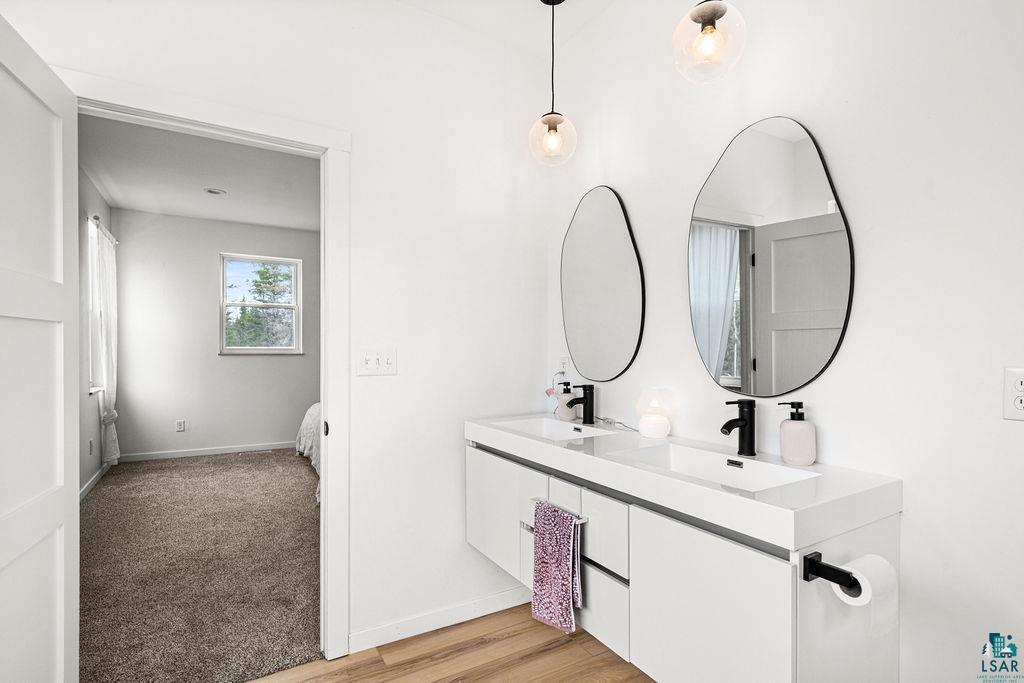 1825 East Shilhon Road Duluth, MN 55804 - Photo 27 of 37 Modern double vanity with integrated sinks, black fixtures, and organic-shaped mirrors.