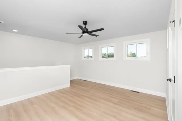 an empty room with wooden floor and windows