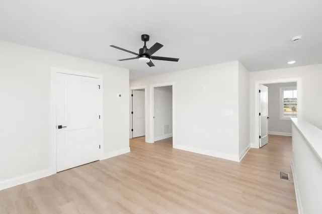 a view of a big room with wooden floor and a ceiling fan