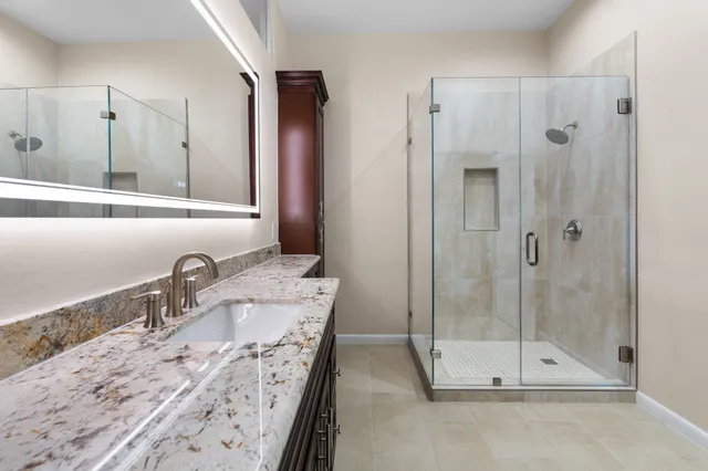 a bathroom with a granite countertop sink vanity and mirror