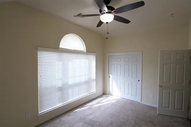 an empty room with windows and fan