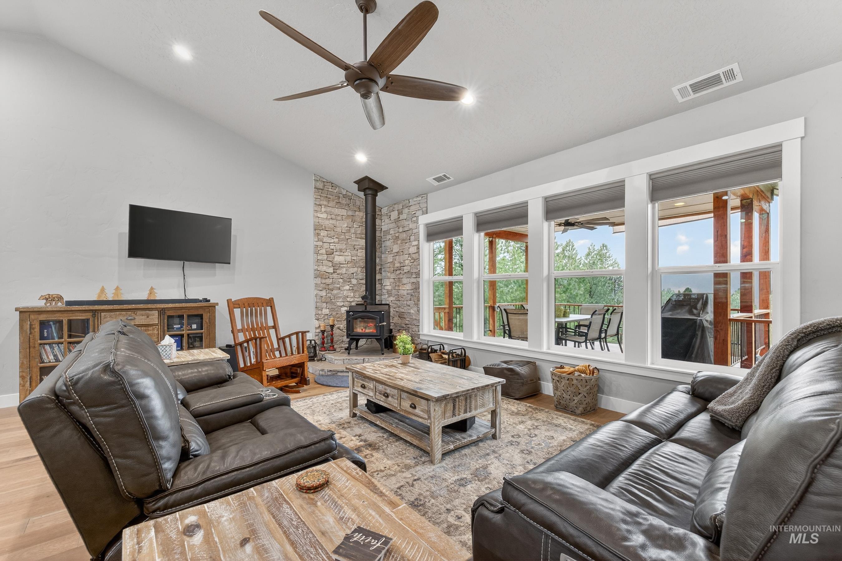 10191 Timberrim Drive Cascade, ID 83611 - Photo 17 of 44 Living room featuring ceiling fan, a wood stove, vaulted ceiling, wood finished floors, and recessed lighting