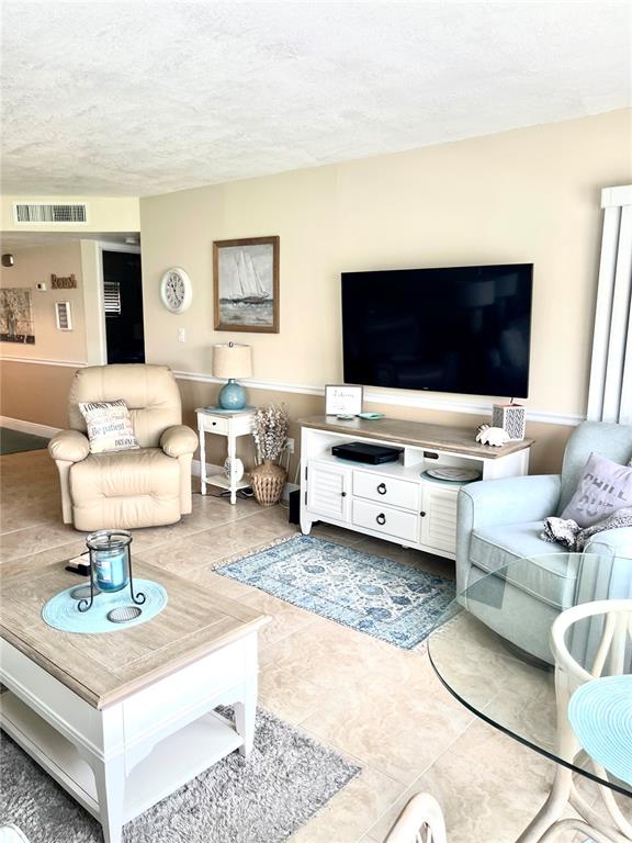 4650 Cove Circle, Unit 402 St. Petersburg, FL 33708 - Photo 12 of 36 a living room with furniture and a flat screen tv