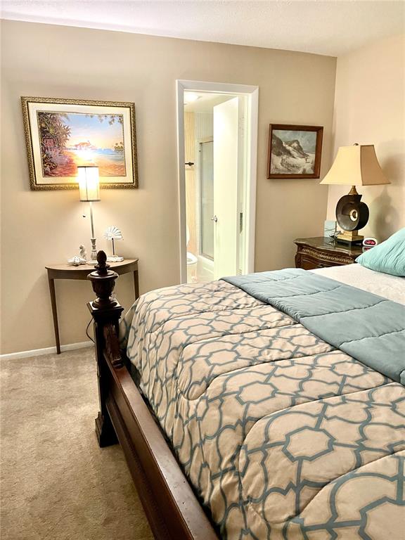 4650 Cove Circle, Unit 402 St. Petersburg, FL 33708 - Photo 20 of 36 a bedroom with a bed and a lamp on dresser
