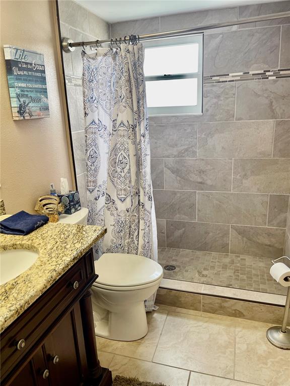 4650 Cove Circle, Unit 402 St. Petersburg, FL 33708 - Photo 5 of 36 a bathroom with a granite countertop sink toilet and shower