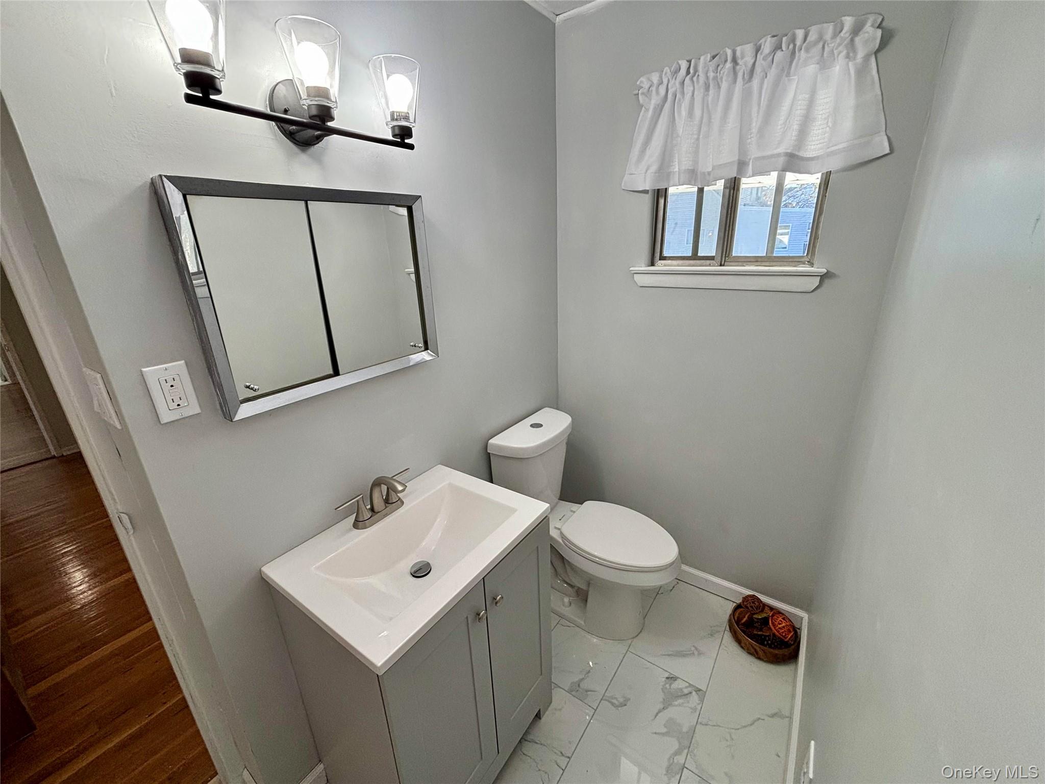 1483 4th Street West Babylon, NY 11704 - Photo 12 of 25 a bathroom with a toilet a sink and mirror