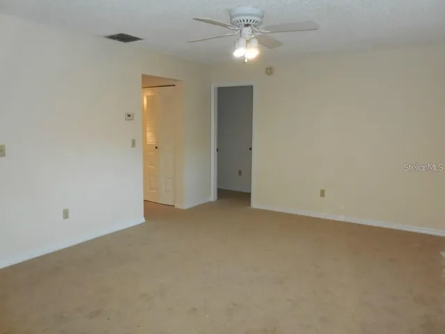 an empty room with a ceiling fan and a window