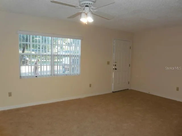 an empty room with a ceiling fan and window