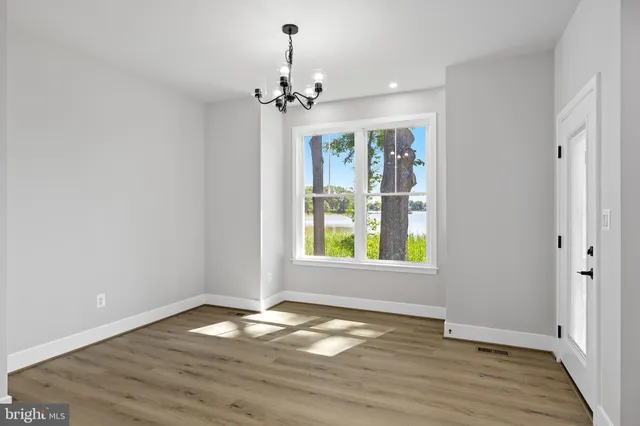 a view of empty room with wooden floor and window