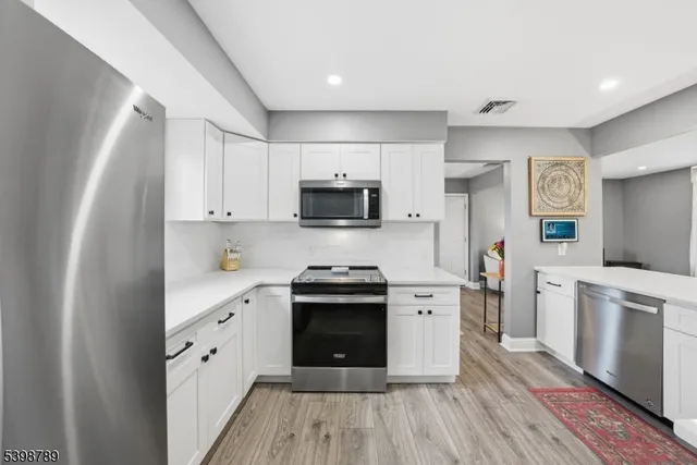 a kitchen with granite countertop white cabinets and stainless steel appliances