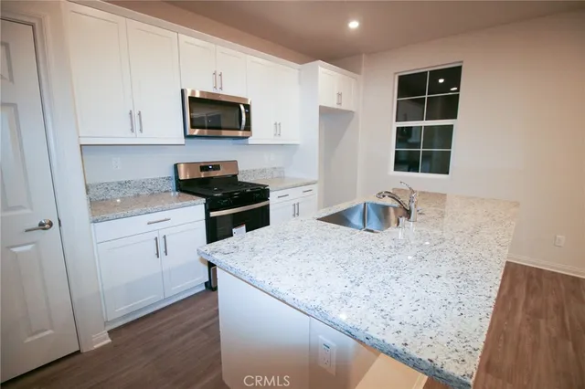 a kitchen with granite countertop a sink a stove and microwave