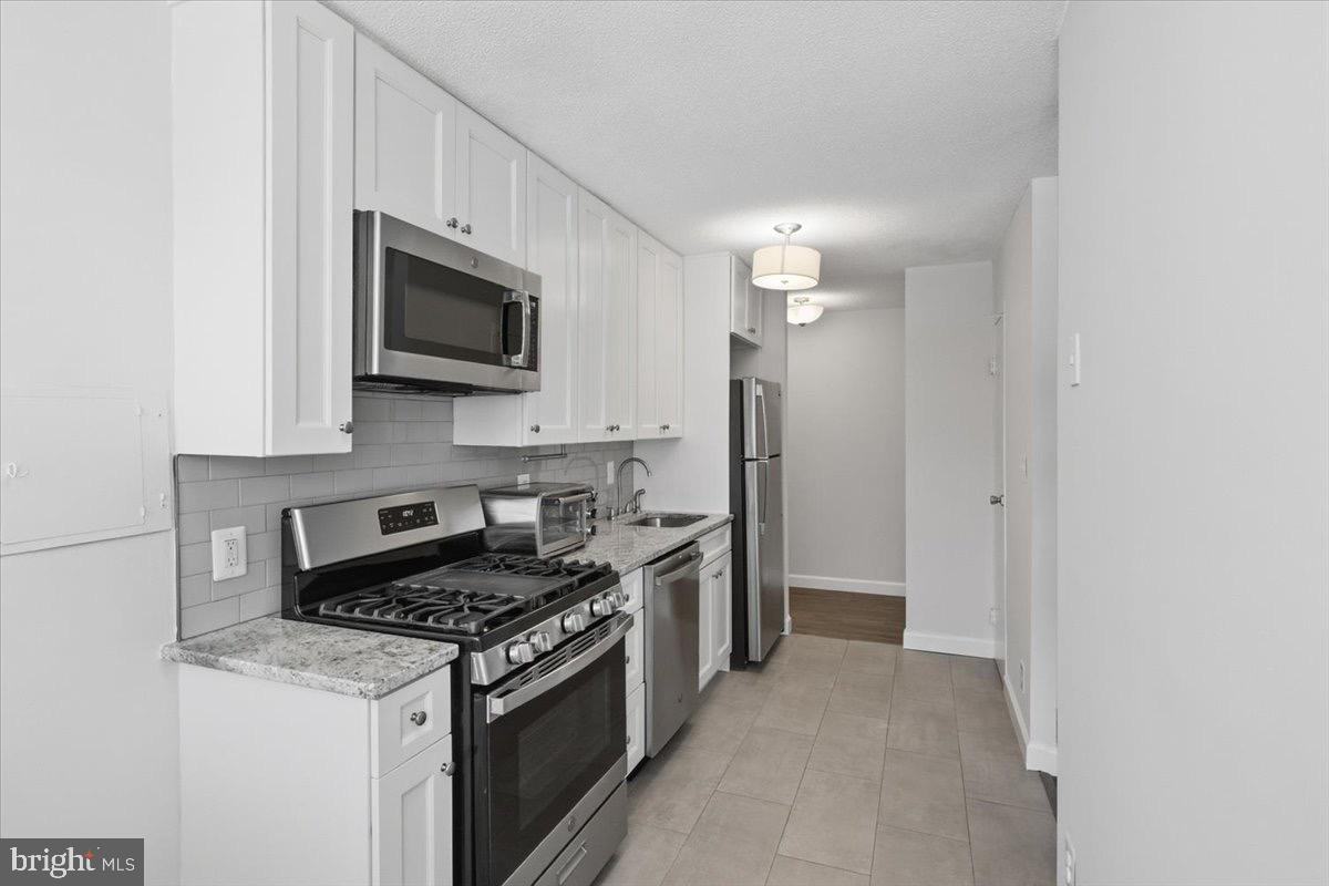 a kitchen with stainless steel appliances granite countertop white cabinets a stove top oven with sink and dishwasher
