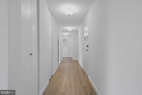 a view of a hallway with wooden floor and closet