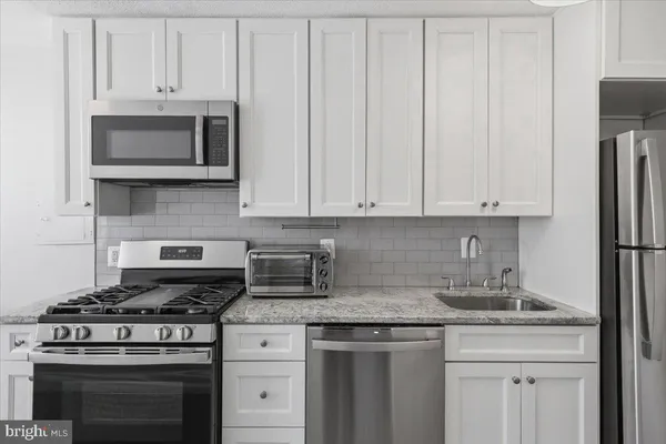 a kitchen with granite countertop white cabinets and stainless steel appliances