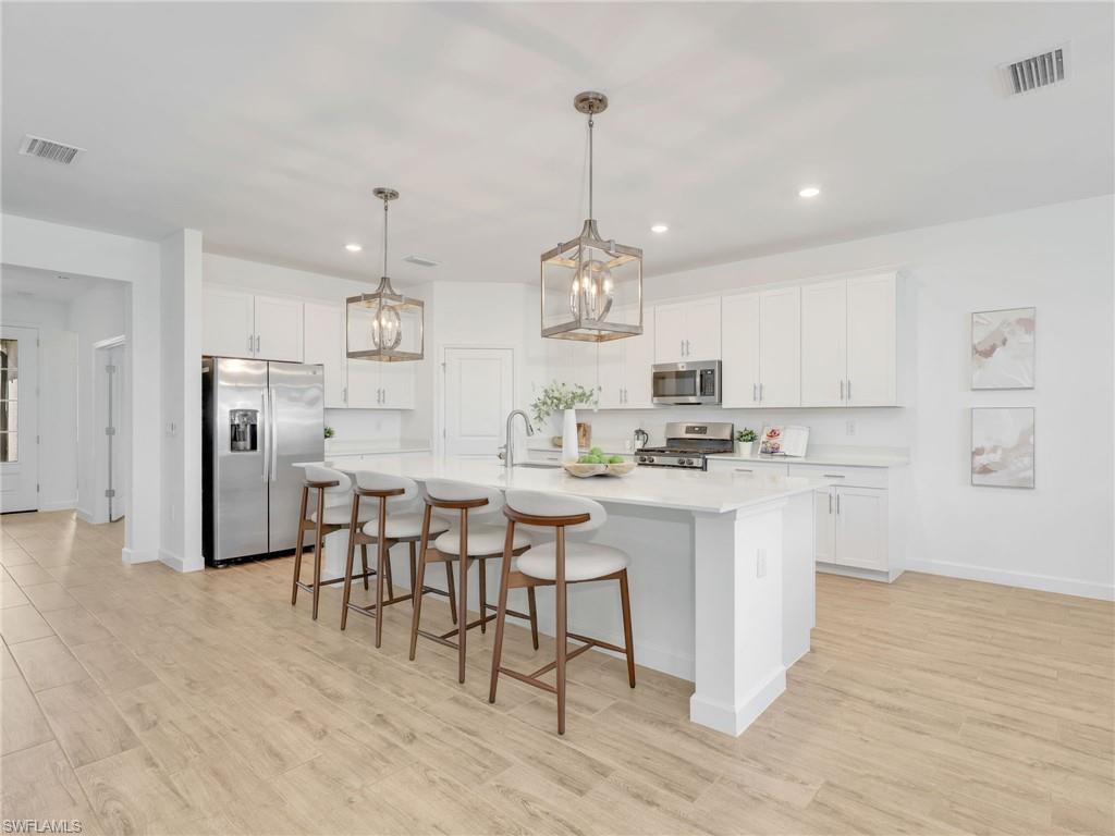 18320 Ridgeline Drive Estero, FL 33928 - Photo 6 of 38 a kitchen with kitchen island granite countertop a sink cabinets and wooden floor