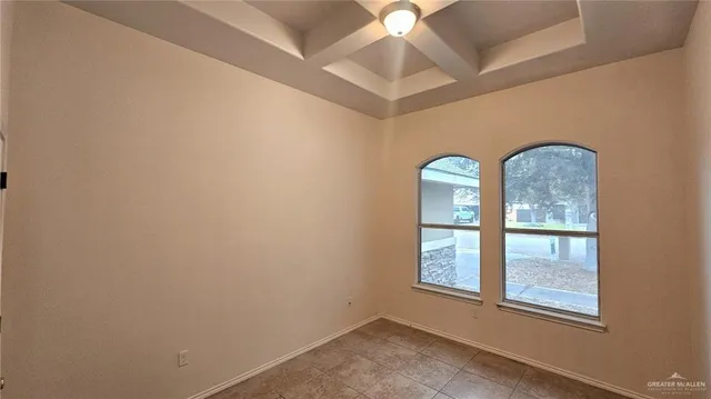 an empty room with windows and chandelier fan