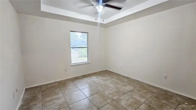 an empty room with a chandelier fan and windows