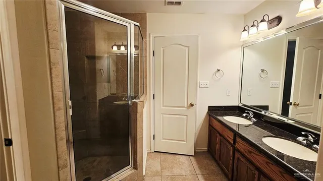 a bathroom with a double vanity sink a mirror and a shower