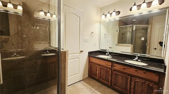 a bathroom with a double vanity sink and mirror with shower