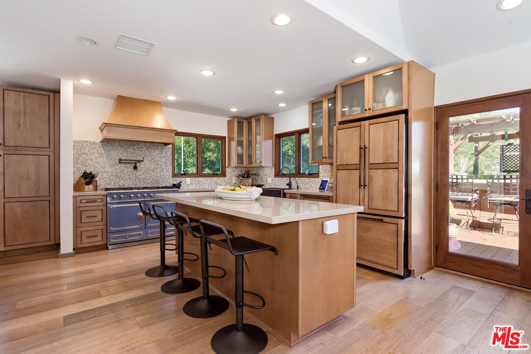 24537 Dry Canyon Cold Creek Road Calabasas, CA 91302 - Photo 13 of 54 a kitchen with stainless steel appliances granite countertop a refrigerator a sink dishwasher a stove and a dining table with wooden floor