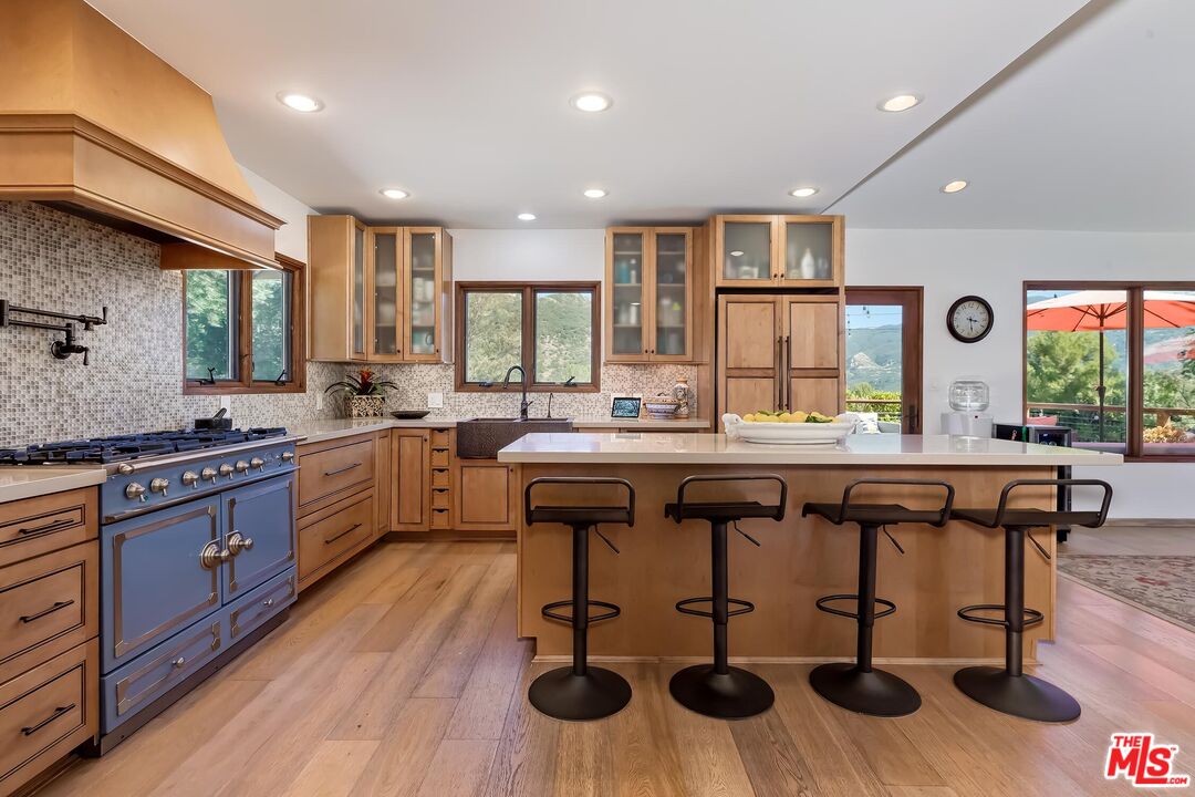 24537 Dry Canyon Cold Creek Road Calabasas, CA 91302 - Photo 15 of 54 a kitchen with stainless steel appliances kitchen island granite countertop a table chairs sink and cabinets