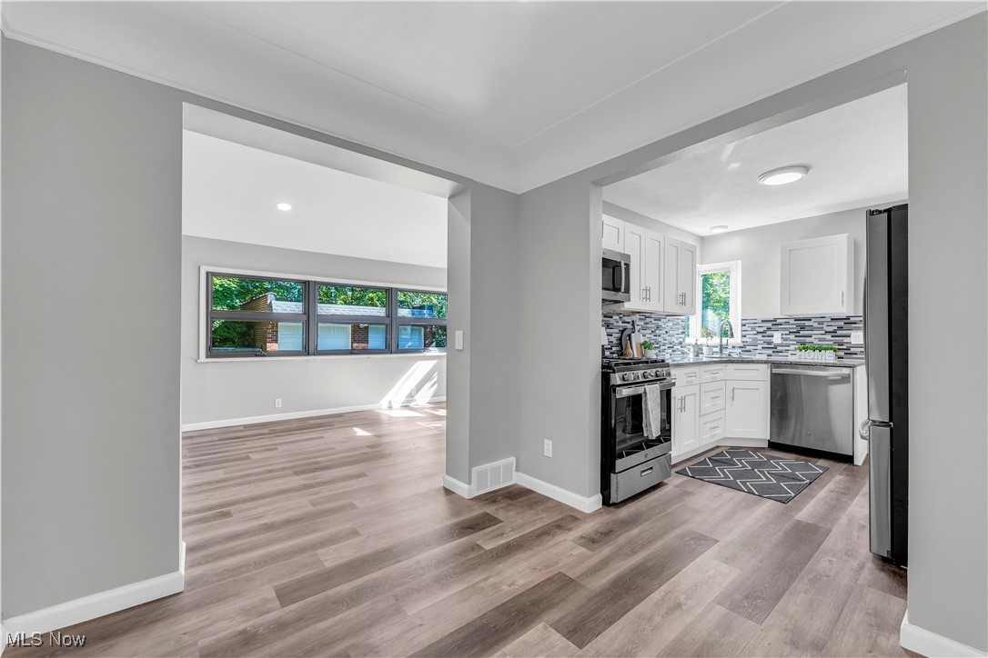 2425 Canterbury Road Cleveland Heights, OH 44118 - Photo 13 of 33 Kitchen with appliances with stainless steel finishes, decorative backsplash, light hardwood / wood-style floors, and white cabinetry