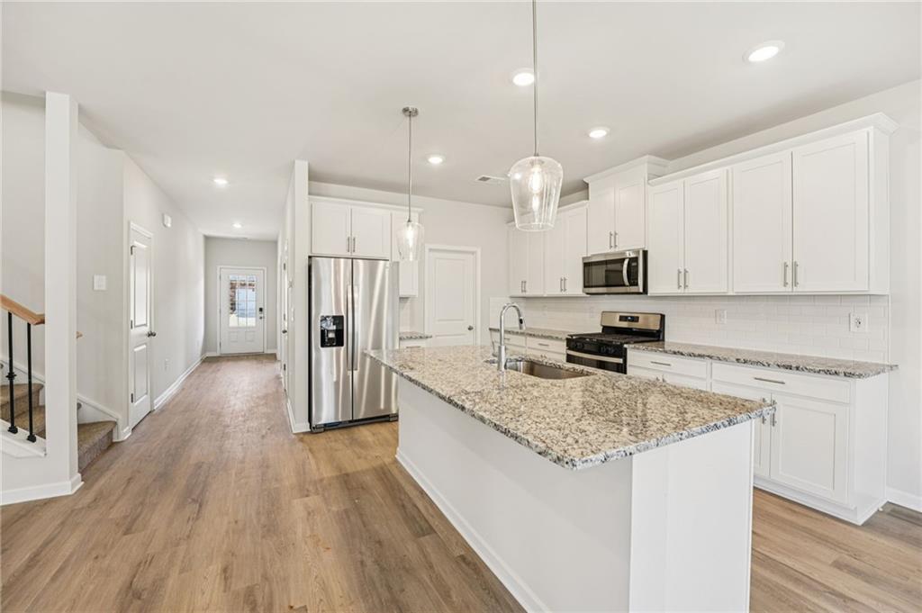 4412 Brick Tunl Street Powder Springs, GA 30127 - Photo 23 of 72 a kitchen with stainless steel appliances granite countertop a refrigerator a stove a sink and white cabinets with wooden floor