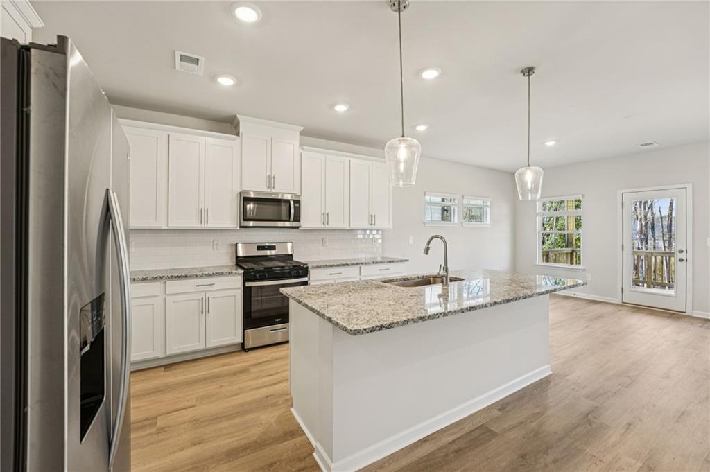 4412 Brick Tunl Street Powder Springs, GA 30127 - Photo 26 of 72 a large kitchen with granite countertop a stove a sink a refrigerator and a dining table