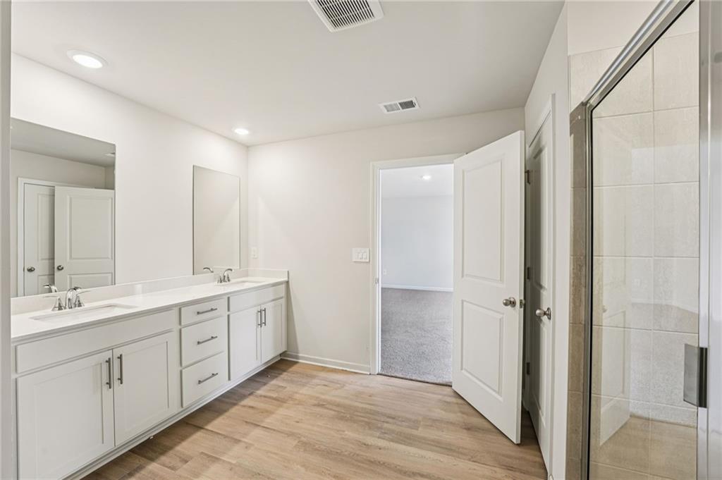 4412 Brick Tunl Street Powder Springs, GA 30127 - Photo 50 of 72 a spacious bathroom with a double vanity sink a large mirror and shower