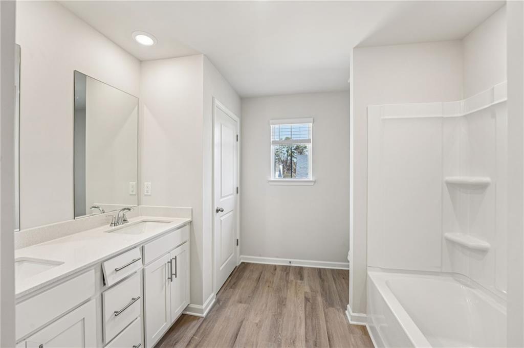 4412 Brick Tunl Street Powder Springs, GA 30127 - Photo 55 of 72 a bathroom with a double vanity sink a mirror and a bathtub