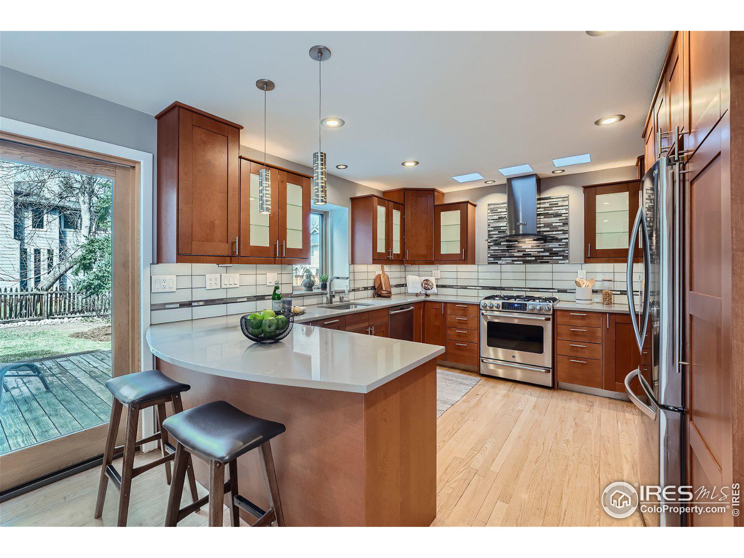 a kitchen with kitchen island granite countertop wooden floors and a refrigerator