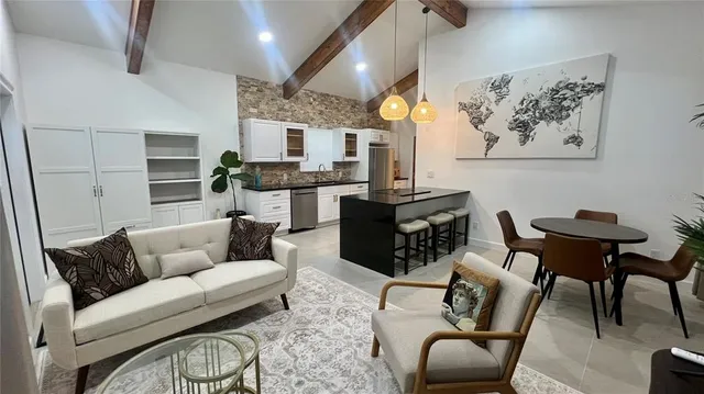 a living room with furniture a flat screen tv and kitchen view