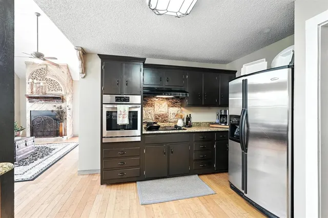 a kitchen with stainless steel appliances granite countertop a refrigerator and a stove top oven