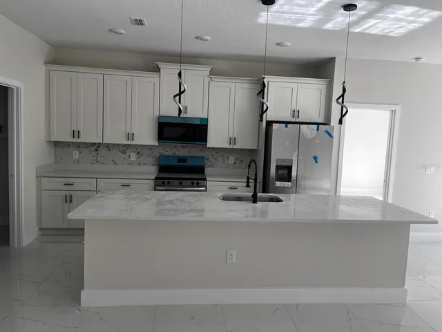 a kitchen with stainless steel appliances granite countertop a sink a refrigerator and a granite counter tops