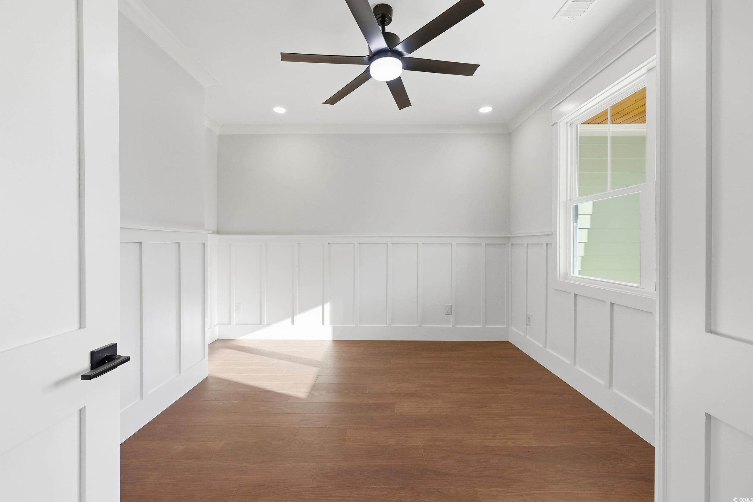 813 Commanders Island Road Georgetown, SC 29440 - Photo 9 of 39 Unfurnished room with wainscoting, a decorative wall, dark wood-type flooring, crown molding, and a ceiling fan