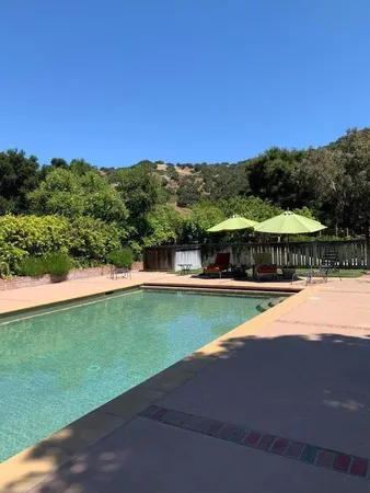 a view of a swimming pool with lawn chairs under an umbrella