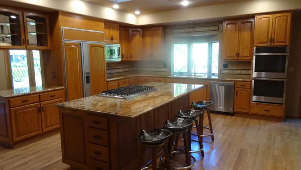 a kitchen with center island wooden floor and stainless steel appliances