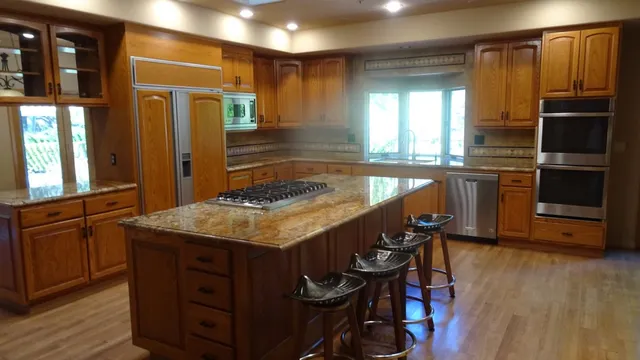 a kitchen with center island wooden floor and stainless steel appliances